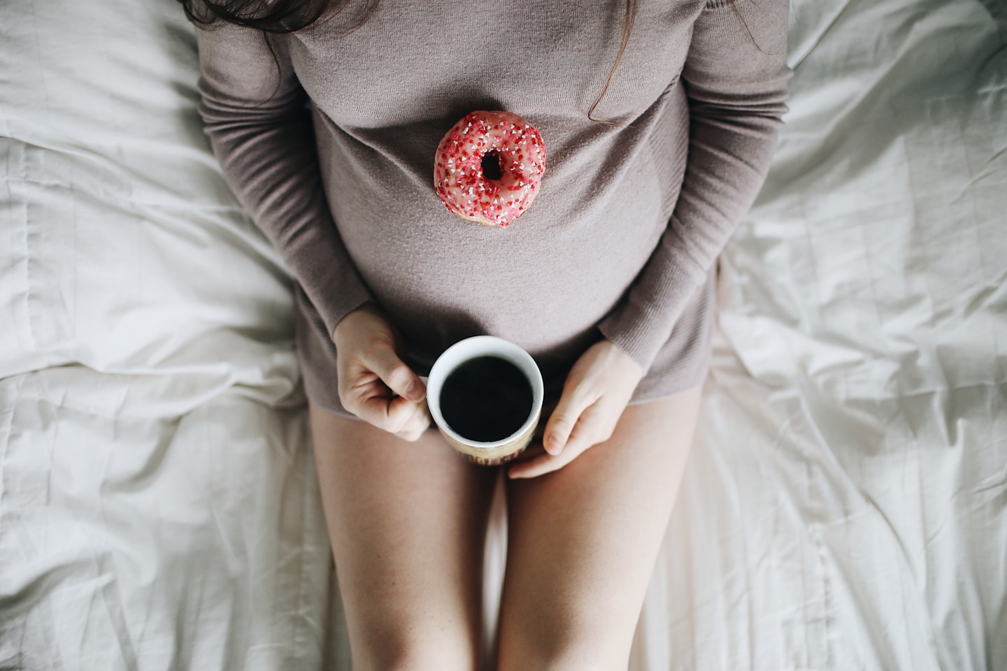 Pregnant belly with donut and coffee