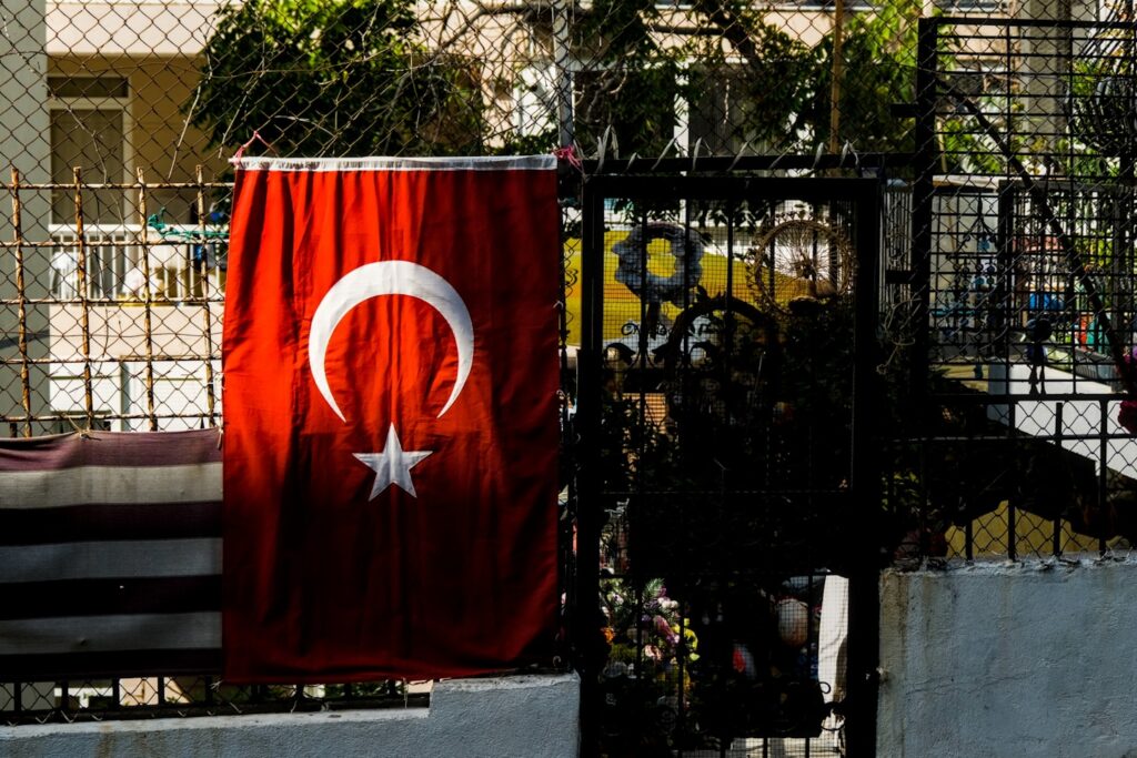 Turkish flag hanging on a fence with plants.