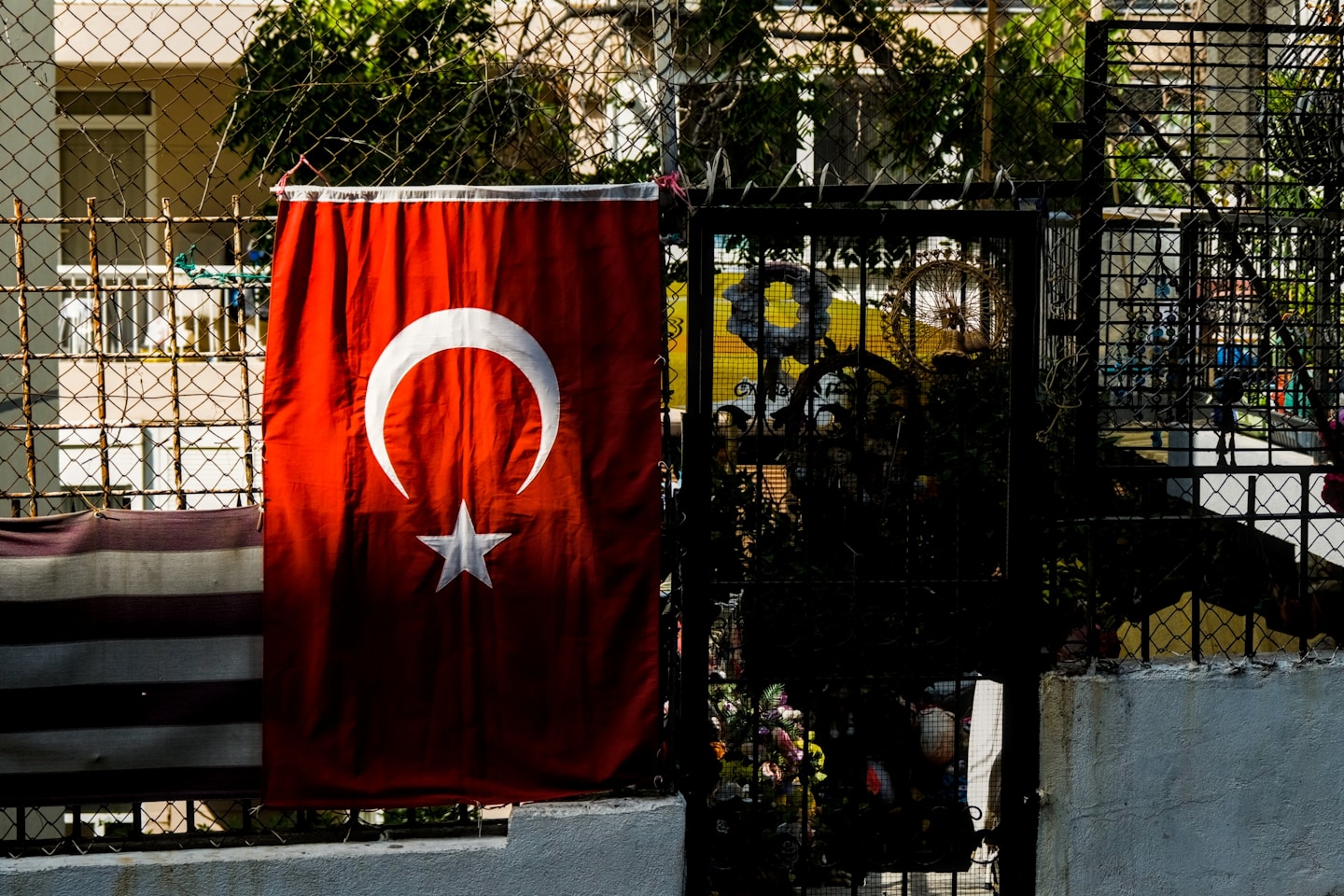 Turkish flag hanging on a fence with plants.