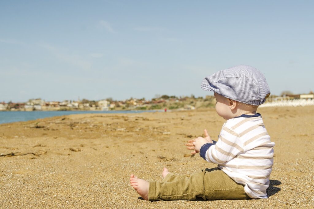 A baby boy sitting on the sand