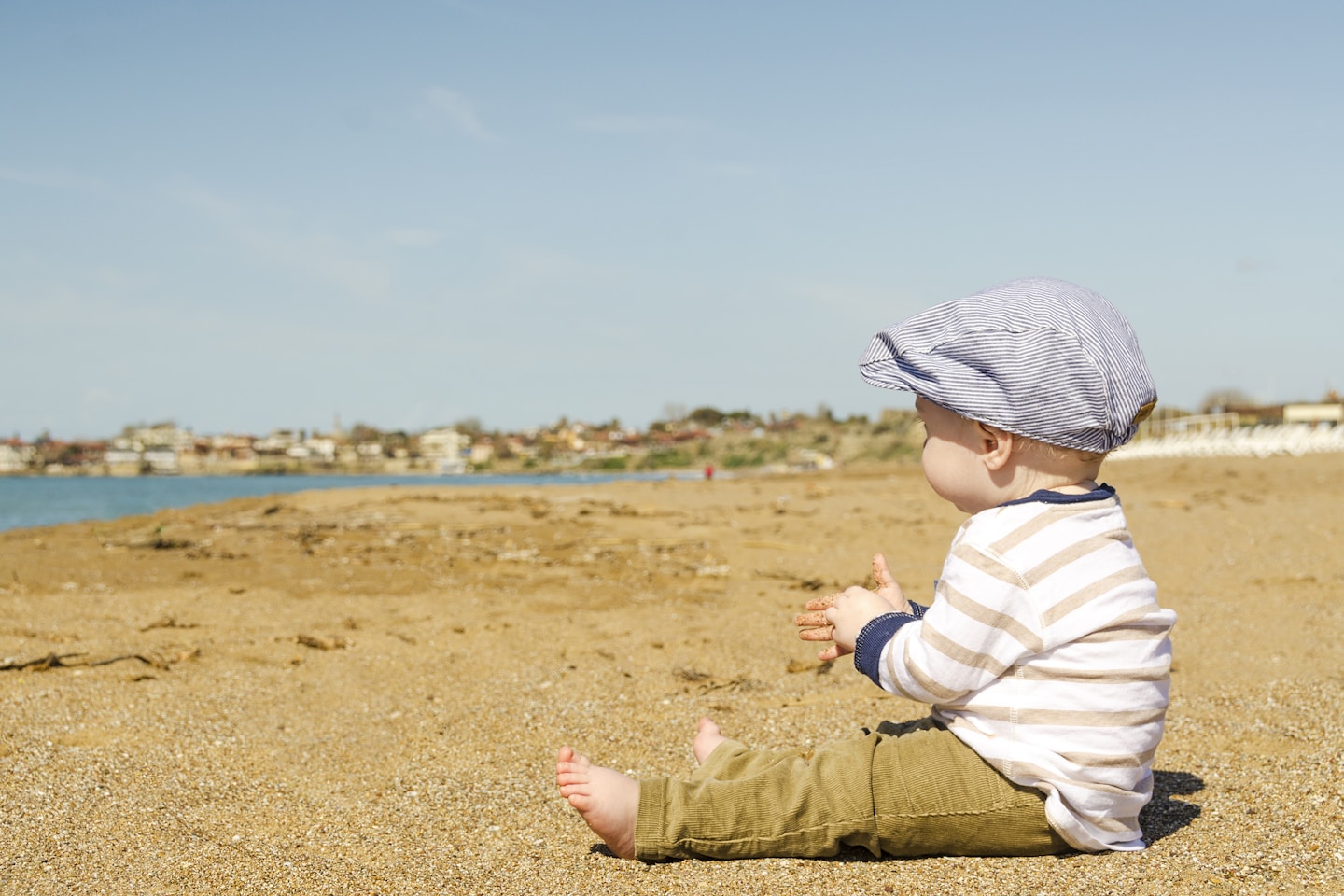 A baby boy sitting on the sand